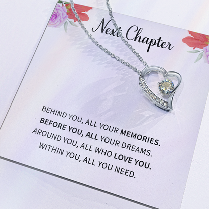 Silver open heart pendant necklace with a center stone, gifted with a "New Chapter" message.

